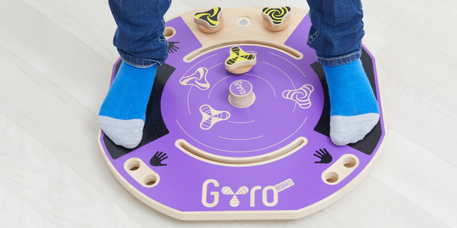Die Füße eines Kindes stehen auf den Anti-Rutsch-Flächen des Gyro-Boards. Er dreht den Kreisel mit Gleichgewichtsverlagerungen.